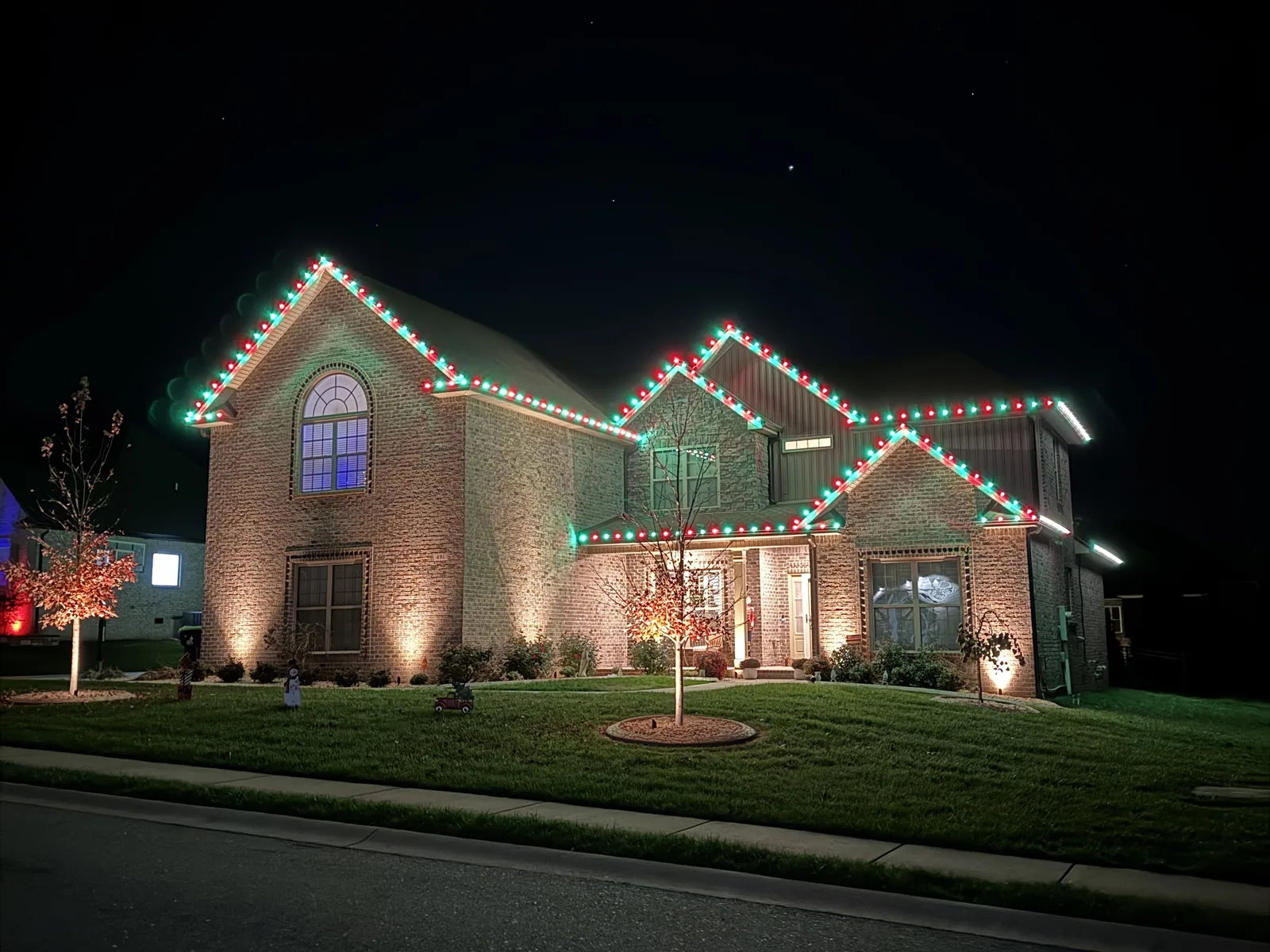 Red and green lights tracing the rooflines of a brick home